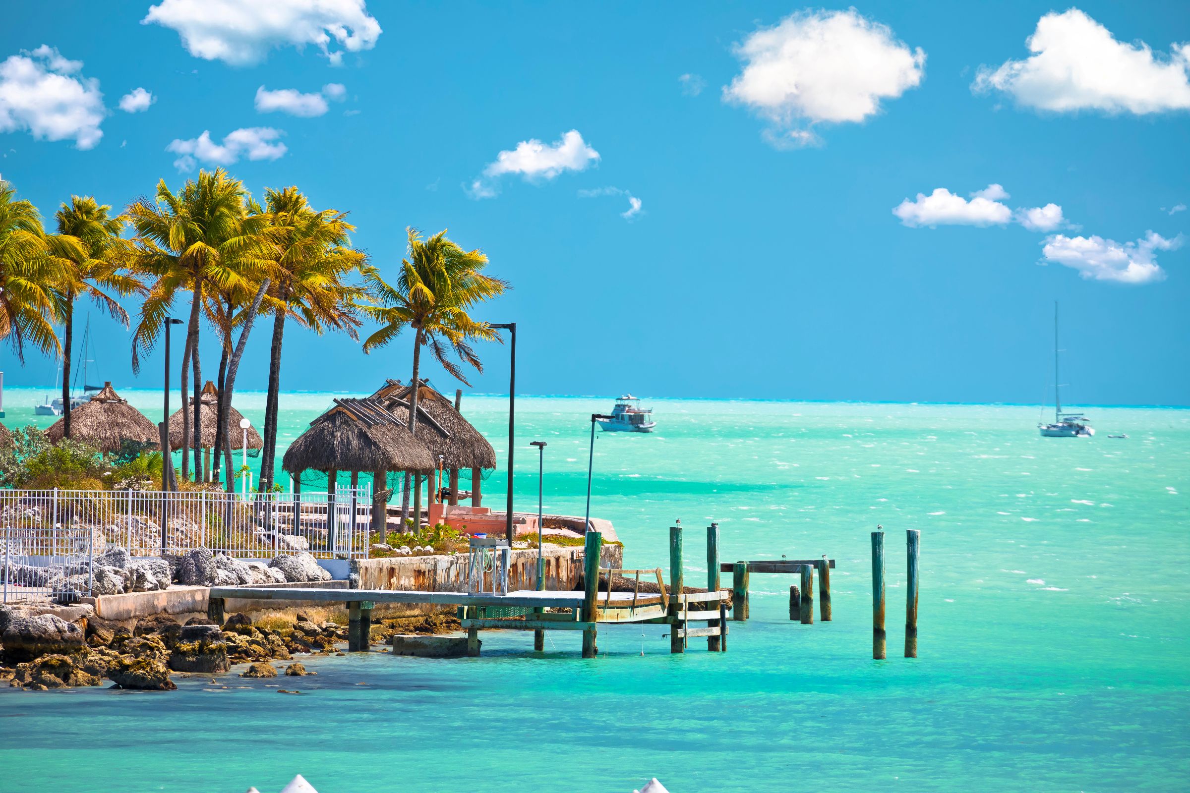 Tiki huts and palm trees beside turquoise water in the Florida Keys
