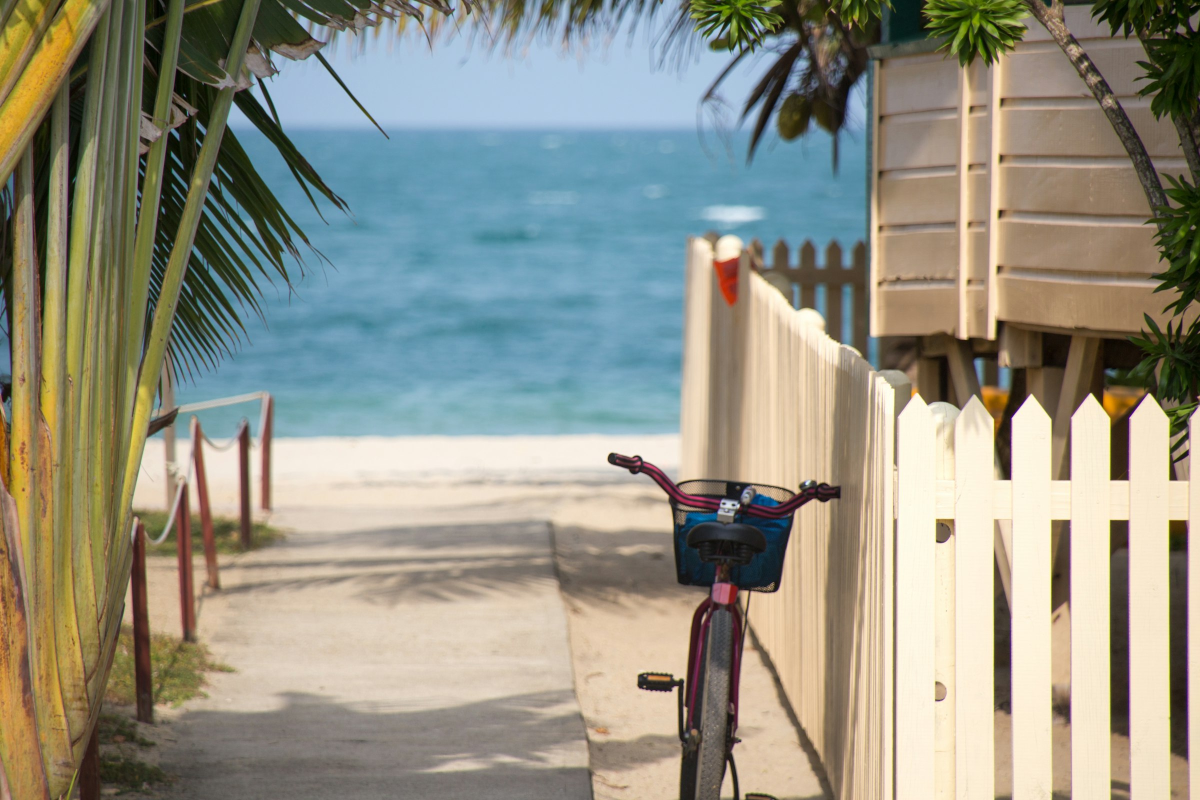 A bicycle parked by a white fence at a Florida Keys beach